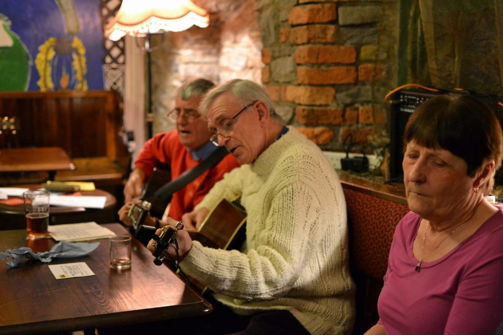 Guto Davies playing an acoustic guitar sat in the bar Bach