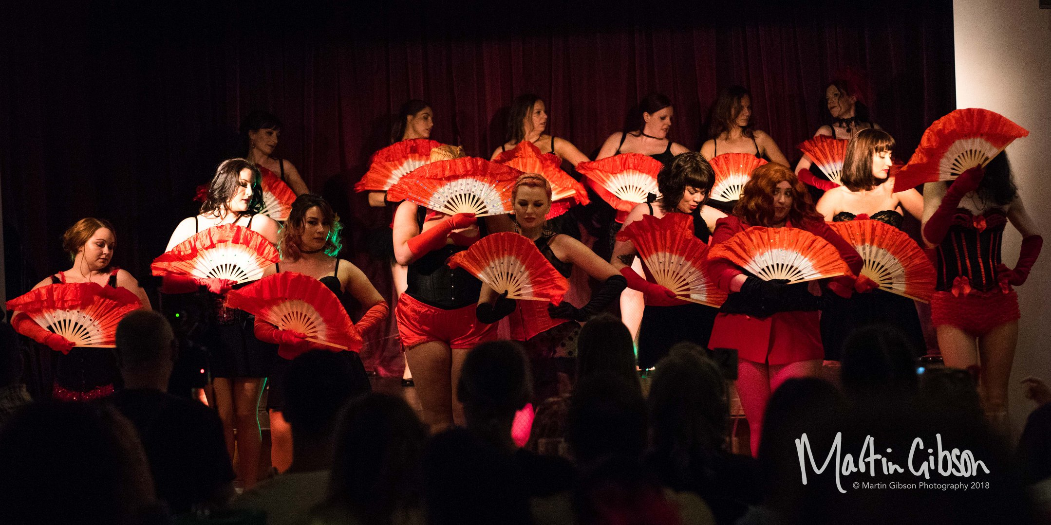 local dancers with red fans on a stage